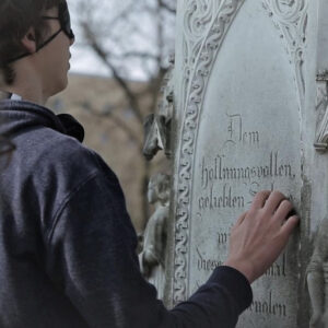 Junge fühlt die Inschrift eines Grabsteines